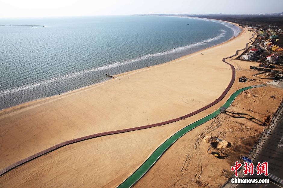 3月13日，秦皇島萬(wàn)米臨海沙灘木棧道。據(jù)了解，該木棧道全長(zhǎng)約4200米，與北戴河區(qū)原有的7500米木棧道對(duì)接后全線總長(zhǎng)度1.17萬(wàn)米，整個(gè)木棧道東起秦皇島體育基地游船碼頭，西至北戴河濕地公園，呈波浪形蜿蜒10.4公里海岸線。 中新社發(fā) 曹建雄 攝 CNSPHOTO